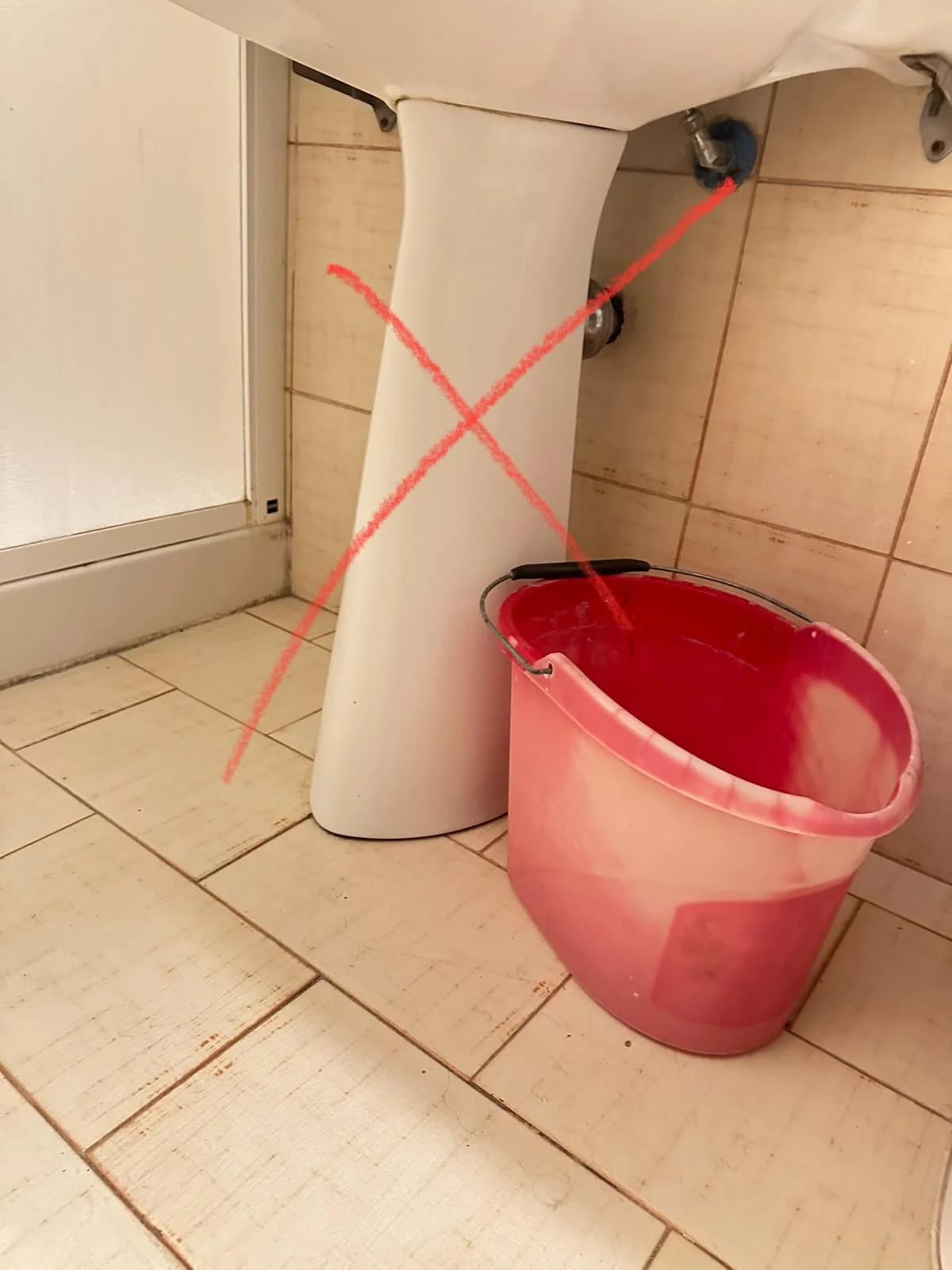 Secchio posizionato sotto un lavabo durante la verifica di una perdita.